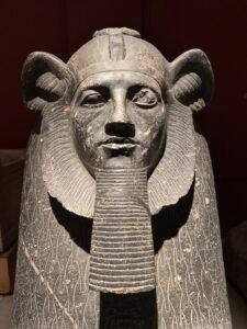 Close frontal view of Pharaoh Amenemhat III on the grey granite Tanis sphinx, JE 15210 / CG 394, showing the lion mane, royal beard and weathered face in the Egyptian Museum in Cairo