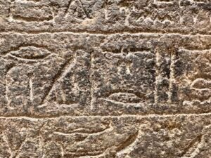 Close-up of heavily weathered ancient Egyptian hieroglyphs carved into rough stone