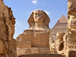Great Sphinx of Giza framed by weathered limestone walls with the Pyramid of Khafre behind it