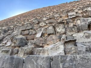 Close view of massive weathered limestone masonry blocks forming the sloping face of a Giza pyramid