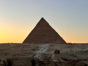 Pyramid of Khafre silhouetted above the Great Sphinx and Giza Plateau in warm sunset light