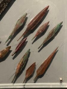 Group of New Kingdom bronze and copper-alloy arrowheads with leaf-shaped blades and tangs displayed in the military collection at Luxor Museum in Egypt