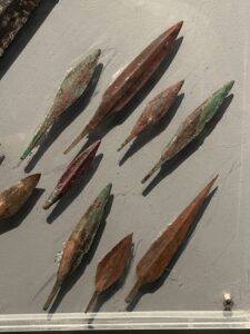 Group of New Kingdom bronze and copper-alloy arrowheads with leaf-shaped blades and tangs displayed in the military collection at Luxor Museum in Egypt