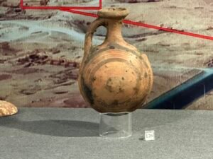 Small round ancient Egyptian pottery jug with one loop handle, narrow neck, and dark painted bands