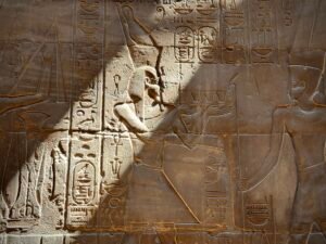 Relief of Alexander the Great portrayed as an Egyptian pharaoh presenting offerings before a deity in the Barque Shrine at Luxor Temple, with his royal cartouches and hieroglyphs