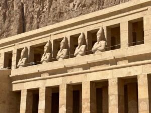 Row of Osiride statues of Pharaoh Hatshepsut with crossed arms and royal regalia along the upper terrace of Djeser-Djeseru at Deir el-Bahari, Luxor