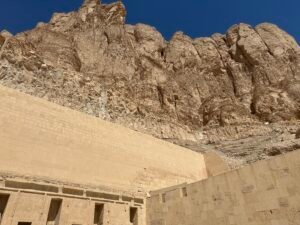 Towering limestone cliffs of Deir el-Bahari rising directly above the upper terrace of Hatshepsut's mortuary temple on Luxor's west bank