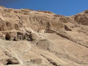 Ancient rock-cut tomb entrances scattered across the dry limestone hills on Luxor's west bank