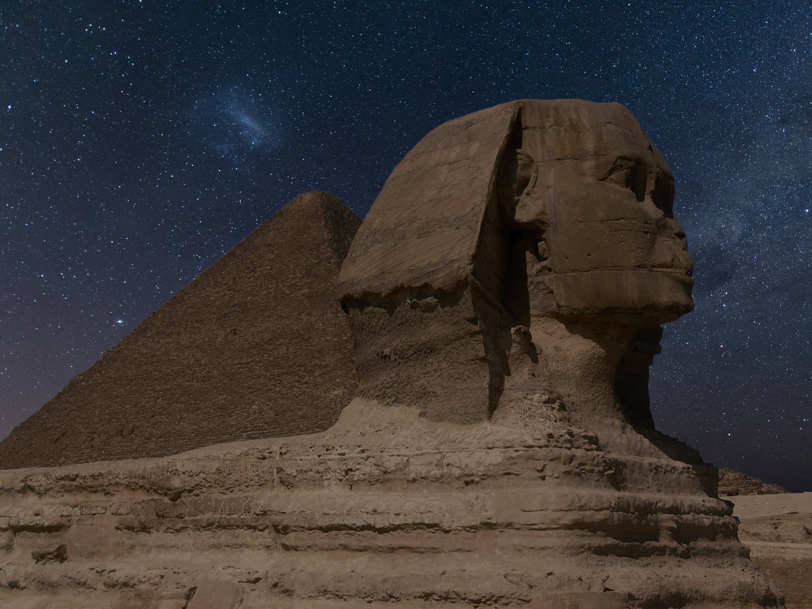 Great Sphinx of Giza with the Pyramid of Khafre behind it beneath a dark star-filled night sky