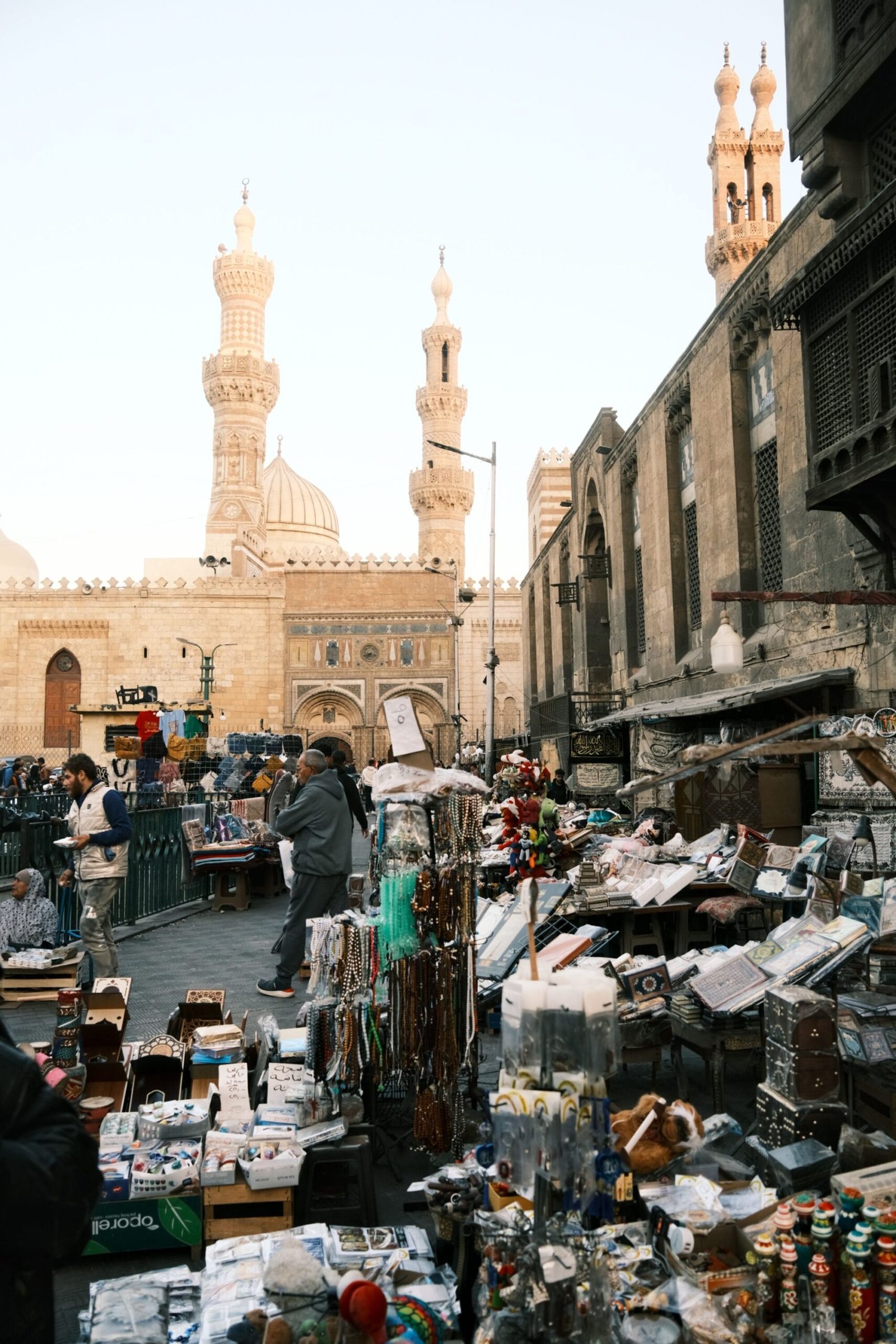 Street vendors displaying souvenirs and small goods beside historic Islamic architecture in Cairo, Egypt