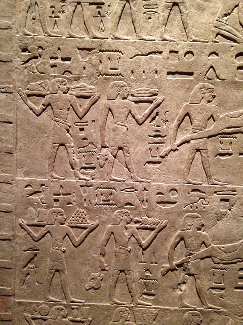 Ancient Egyptian carved relief with figures and rows of hieroglyphic text